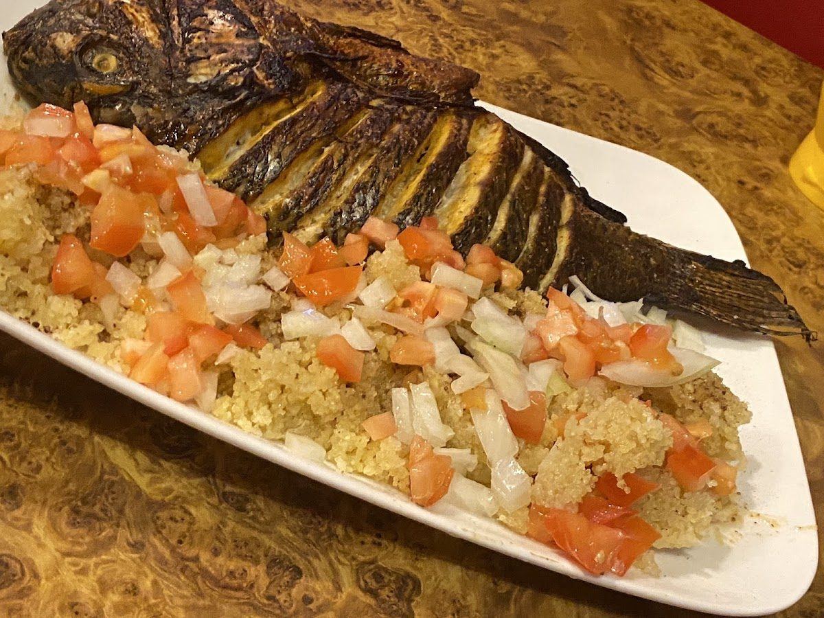 Poisson braisé entier servi avec attiéké, tomates et oignons